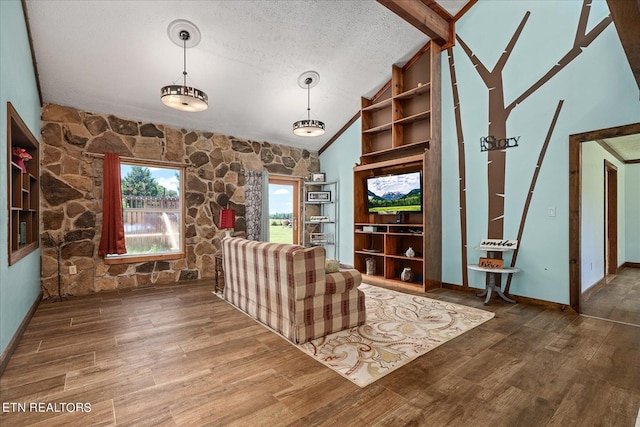 interior space with vaulted ceiling with beams, baseboards, a textured ceiling, and wood finished floors