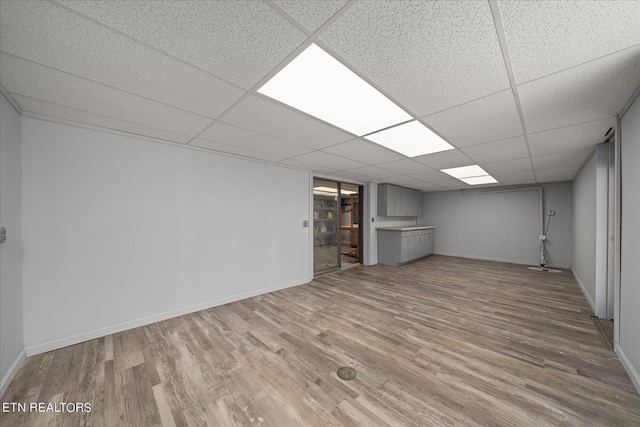 finished basement with a drop ceiling, baseboards, and wood finished floors