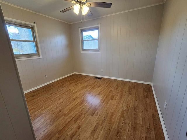 unfurnished room featuring a healthy amount of sunlight, crown molding, visible vents, and wood finished floors