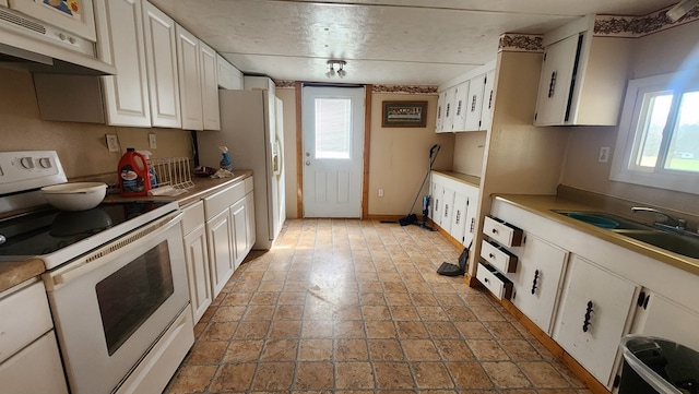 kitchen featuring light countertops, white appliances, plenty of natural light, and white cabinetry