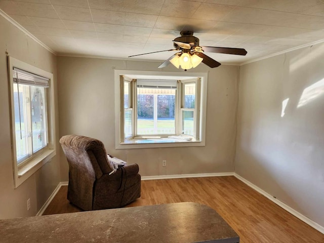 living area featuring a wealth of natural light, crown molding, and wood finished floors