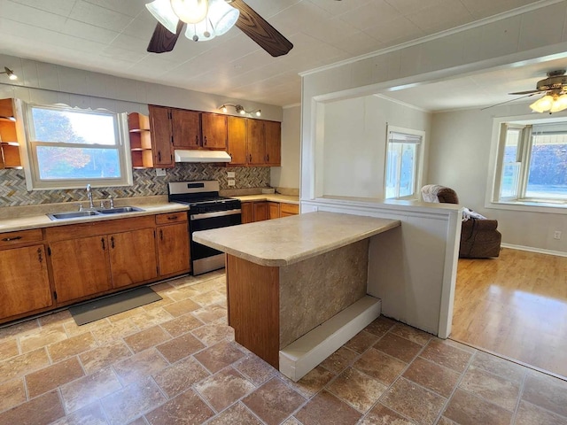 kitchen with a peninsula, light countertops, under cabinet range hood, stainless steel range with gas cooktop, and open shelves