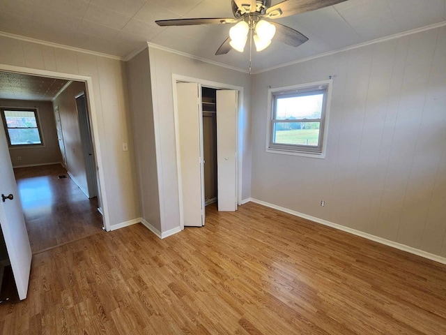 unfurnished bedroom with baseboards, a ceiling fan, ornamental molding, wood finished floors, and a closet