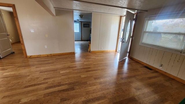 empty room with a healthy amount of sunlight, visible vents, baseboards, and wood finished floors