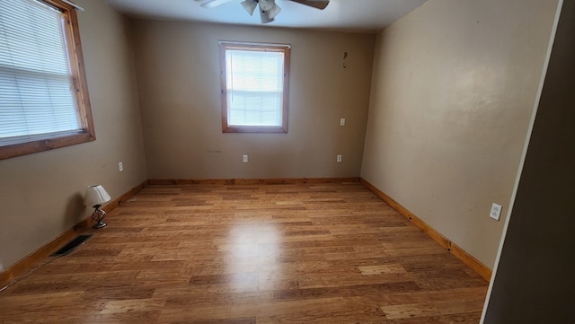 unfurnished room featuring a ceiling fan, baseboards, visible vents, and wood finished floors