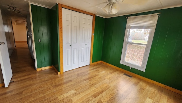 unfurnished bedroom with washer / dryer, a closet, light wood-type flooring, and visible vents