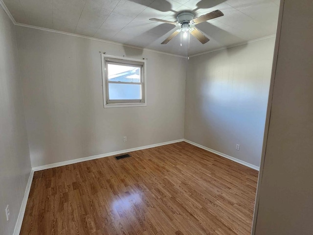 spare room with visible vents, crown molding, and light wood finished floors