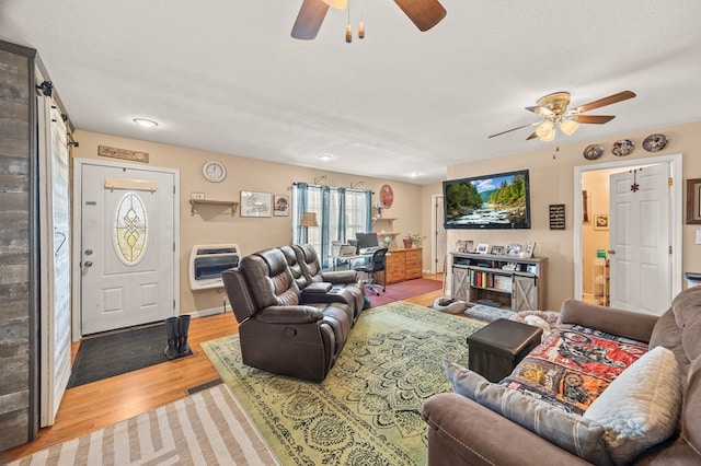 living area with heating unit, light wood-style flooring, a ceiling fan, a textured ceiling, and baseboards