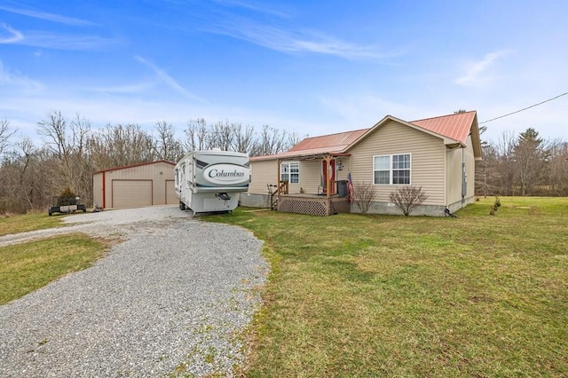 view of front of home featuring an outbuilding, metal roof, a front yard, and a detached garage