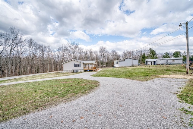 view of front of home featuring gravel driveway, an outdoor structure, and a front lawn