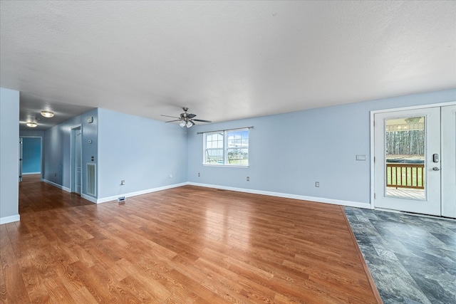 unfurnished living room with a ceiling fan, a textured ceiling, baseboards, and wood finished floors