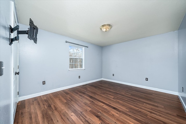 spare room with dark wood-style flooring and baseboards