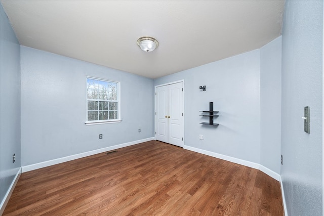 unfurnished room featuring visible vents, baseboards, and wood finished floors