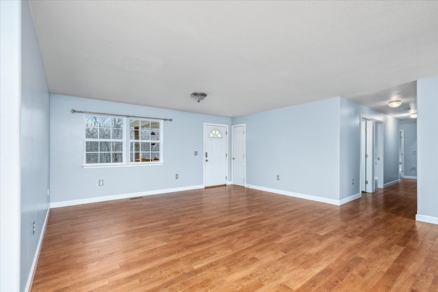 interior space featuring light wood-type flooring, visible vents, and baseboards