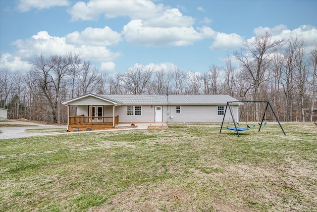 rear view of house with metal roof, a trampoline, and a lawn