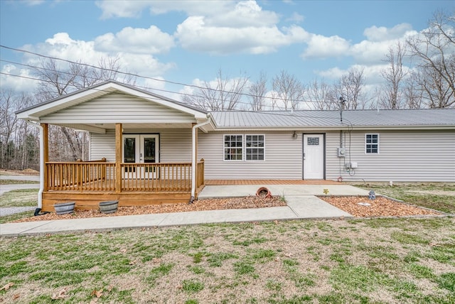 view of front of house featuring french doors, metal roof, and a front lawn