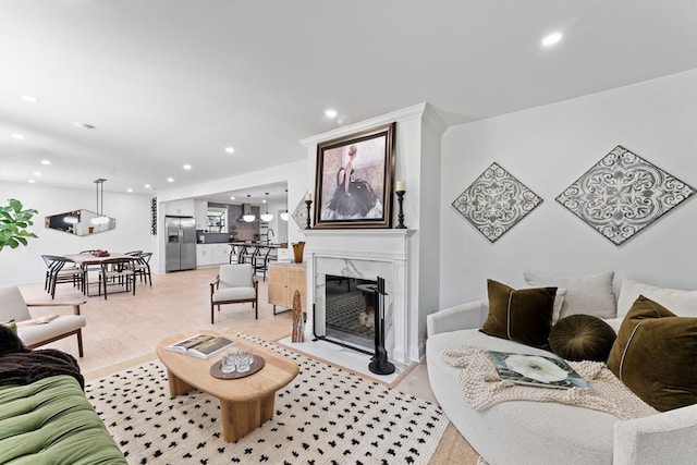 living room featuring recessed lighting, light wood-style flooring, and a premium fireplace