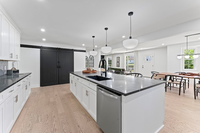 kitchen featuring a spacious island, stainless steel dishwasher, a barn door, white cabinets, and a sink