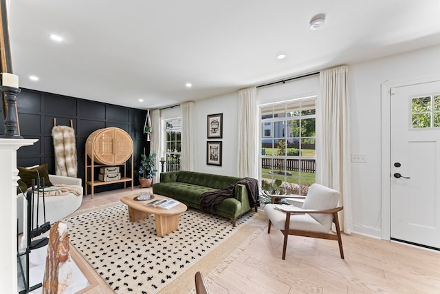 living area with light wood-style floors, a decorative wall, and recessed lighting