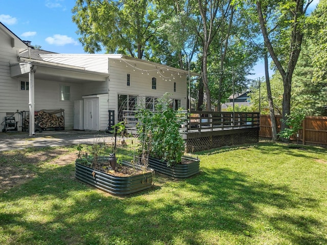 view of yard with fence, a vegetable garden, and a wooden deck