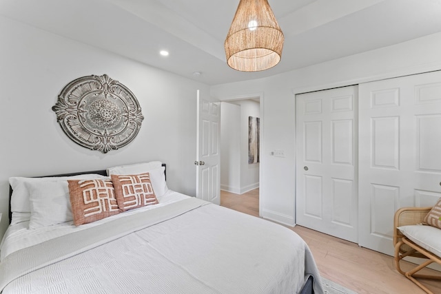 bedroom with a closet, baseboards, wood finished floors, and recessed lighting