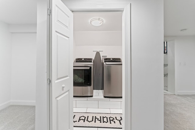 kitchen with baseboards, washing machine and clothes dryer, and light colored carpet