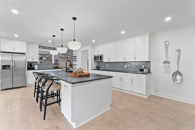 kitchen with appliances with stainless steel finishes, an island with sink, and white cabinetry