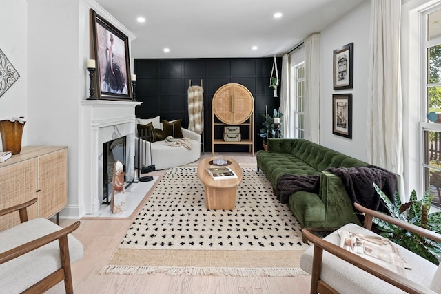 living room with an accent wall, recessed lighting, a fireplace, and light wood finished floors