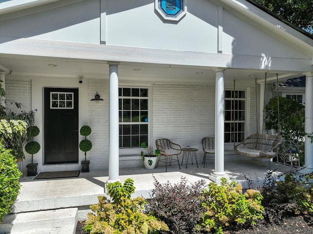 entrance to property featuring covered porch and brick siding