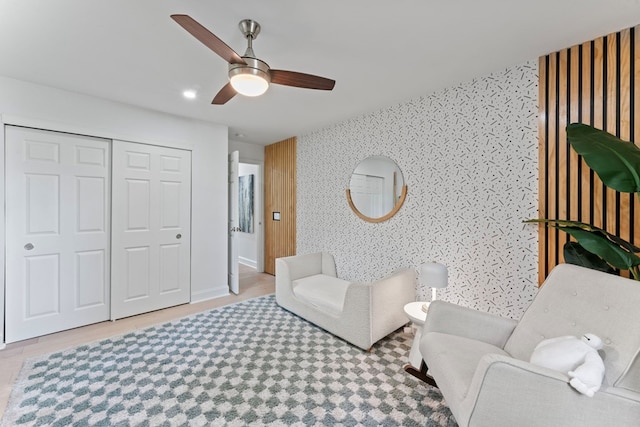 living area featuring a ceiling fan and wallpapered walls