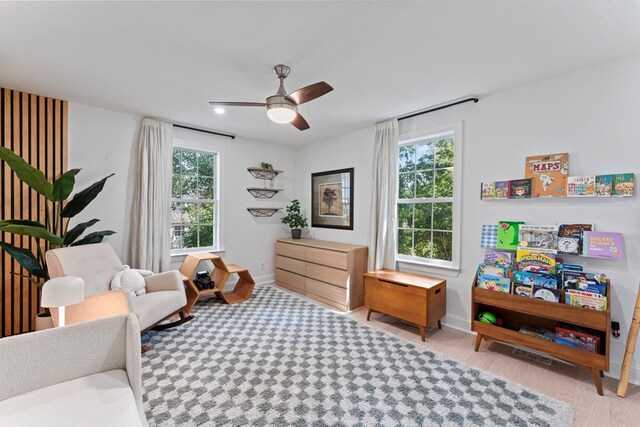 living area featuring light wood-style floors, ceiling fan, and baseboards