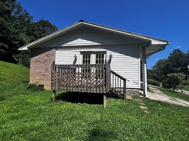 back of house featuring a yard, brick siding, and a wooden deck