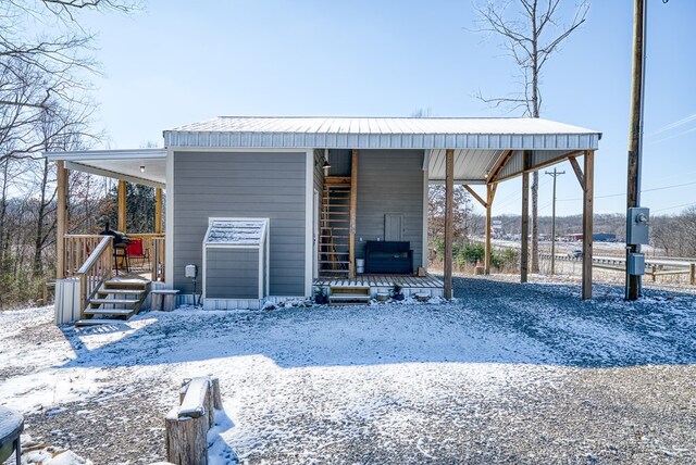 snow covered structure with a carport and driveway