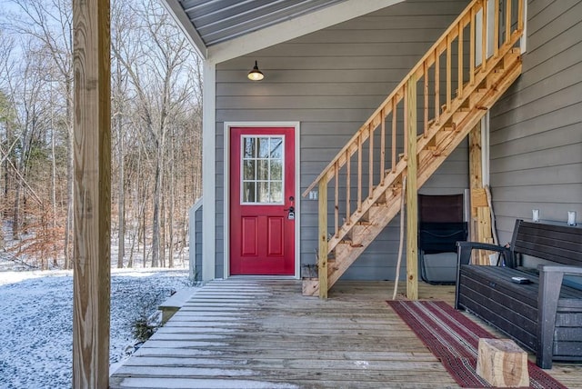 snow covered property entrance featuring a deck