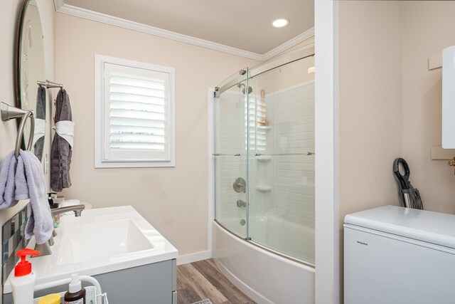 bathroom with shower / bath combination with glass door, ornamental molding, vanity, wood finished floors, and baseboards