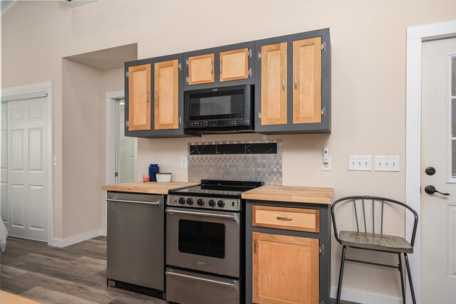 kitchen with black microwave, dark wood-type flooring, baseboards, tasteful backsplash, and stainless steel range with electric stovetop