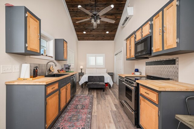 kitchen with wood finished floors, a sink, wood counters, an AC wall unit, and appliances with stainless steel finishes