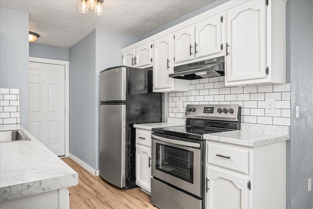 kitchen with stainless steel appliances, white cabinets, light countertops, and under cabinet range hood