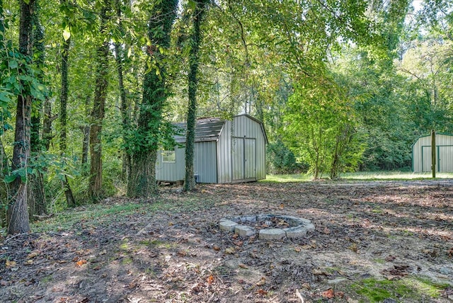 view of yard with an outbuilding, a fire pit, and a shed