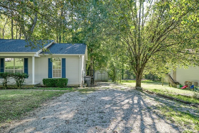 exterior space with a shingled roof and a front yard