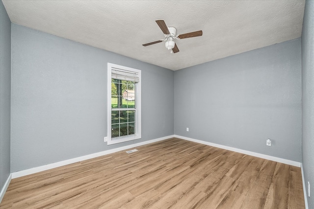 spare room with a textured ceiling, a ceiling fan, light wood-style flooring, and baseboards