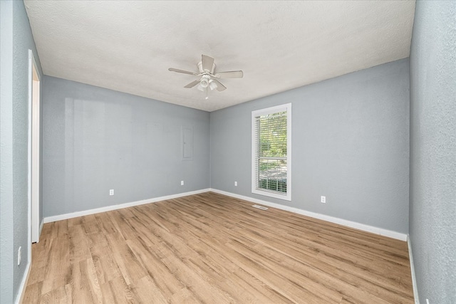 empty room featuring light wood finished floors, visible vents, baseboards, a ceiling fan, and a textured ceiling