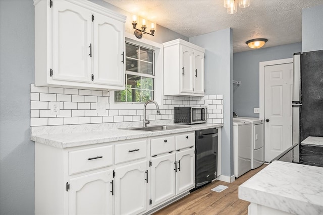 kitchen with light countertops, separate washer and dryer, a sink, and white cabinetry