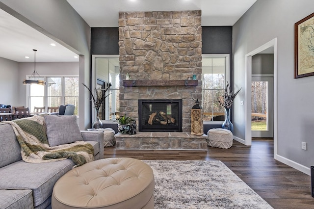 living room featuring dark wood-style floors, a stone fireplace, recessed lighting, and baseboards