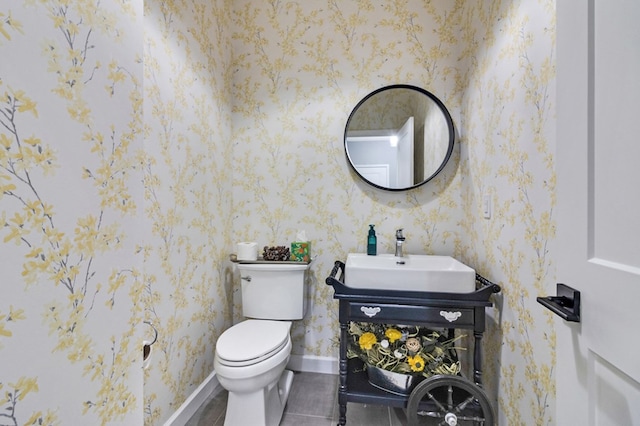 bathroom with toilet, wallpapered walls, baseboards, and vanity