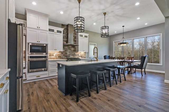 kitchen with a center island with sink, glass insert cabinets, appliances with stainless steel finishes, light countertops, and a sink