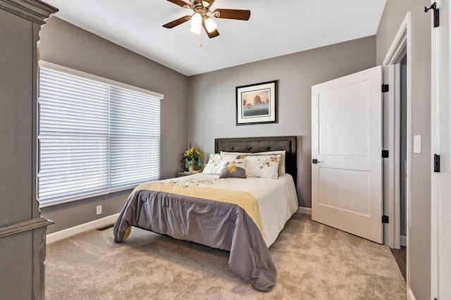 bedroom with a ceiling fan, light colored carpet, visible vents, and baseboards