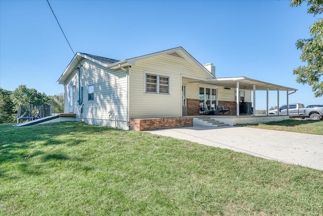 view of front facade with concrete driveway, a porch, a trampoline, and a front yard