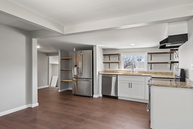 kitchen with light stone counters, dark wood finished floors, open shelves, appliances with stainless steel finishes, and wall chimney range hood