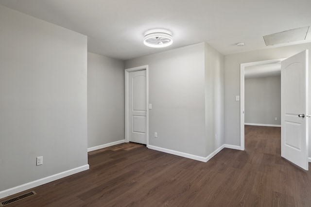 unfurnished room featuring visible vents, baseboards, and dark wood-style flooring